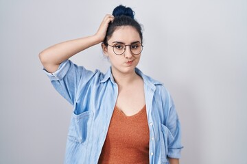 Canvas Print - Young modern girl with blue hair standing over white background confuse and wondering about question. uncertain with doubt, thinking with hand on head. pensive concept.