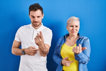 Poster - Young brazilian mother and son standing over blue background beckoning come here gesture with hand inviting welcoming happy and smiling