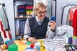 © Krakenimages.com - Young blond man tailor using smartphone writing on notebook at clothing factory