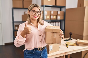 Wall Mural - Young hispanic woman working at small business ecommerce smiling happy and positive, thumb up doing excellent and approval sign