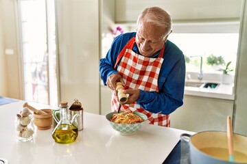 Poster - Senior man smiling confident pouring pepper on spaghetti at kitchen