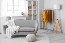Interior Of Living Room With Rack, Sweaters And Sofa