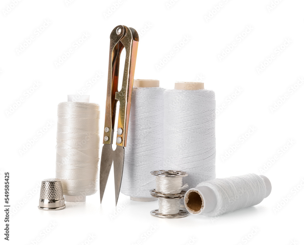 Thread spools, thimble and cutter on white background