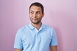 © Krakenimages.com - Hispanic man standing over pink background smiling looking to the side and staring away thinking.
