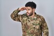© Krakenimages.com - Arab man wearing camouflage army uniform very happy and smiling looking far away with hand over head. searching concept.