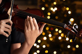 Teen playing violin in formal wear on christmas background