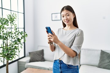 Wall Mural - Young asian woman using smartphone at the living room