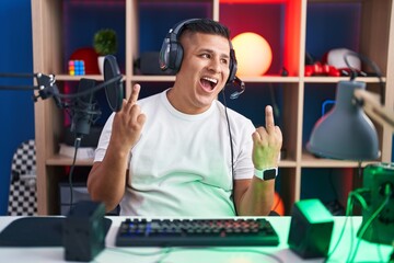 Canvas Print - Young hispanic man playing video games showing middle finger doing fuck you bad expression, provocation and rude attitude. screaming excited