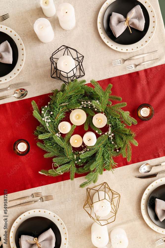 Christmas table setting with wreath and candles in dining room, top view
