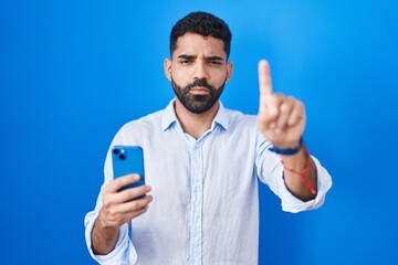 Poster - Hispanic man with beard using smartphone typing message pointing with finger up and angry expression, showing no gesture