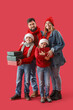 © Pixel-Shot - Little children with Christmas gifts and their parents on red background