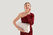 © Pixel-Shot - Young woman in red dress with Christmas gift on grey background