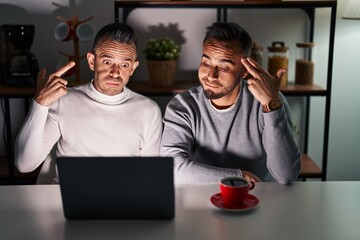 Wall Mural - Homosexual couple using computer laptop shooting and killing oneself pointing hand and fingers to head like gun, suicide gesture.