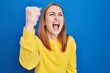 © Krakenimages.com - Young woman standing over blue background angry and mad raising fist frustrated and furious while shouting with anger. rage and aggressive concept.