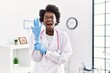 © Krakenimages.com - African doctor woman wearing latex gloves at medical clinic angry and mad screaming frustrated and furious, shouting with anger. rage and aggressive concept.