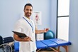 © Krakenimages.com - Young hispanic man physiotherapist smiling confident holding clipboard at rehab clinic