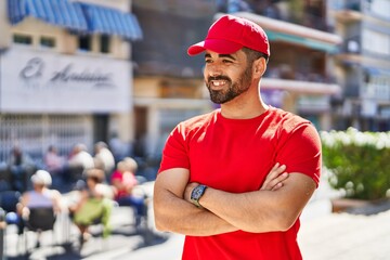 Sticker - Young hispanic man courier standing with arms crossed gesture at street