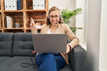 Poster - Young blonde woman working on online appointment smiling happy pointing with hand and finger to the side