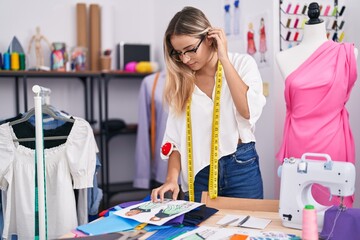 Canvas Print - Young blonde woman tailor looking clothing design standing at clothing shop