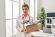© Krakenimages.com - Young doctor woman holding box with medical items skeptic and nervous, frowning upset because of problem. negative person.