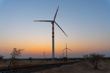 Wall Mural - Pre dawn light in desert sky with Electrical power generating wind mills producing alterative eco friendly green energy for consumption by local people. Thar desert, Rajasthan, India.