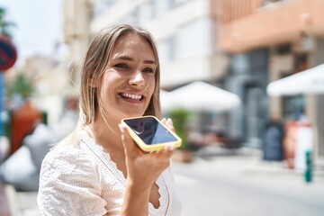 Wall Mural - Young caucasian woman smiling confident talking on the smartphone at street