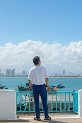 man traveler visiting at Son Tra marina. Tourist with blue dress and hat traveling in Da Nang city. Vietnam and Southeast Asia travel concept