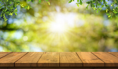 Empty wooden table are placed outdoors on green bokeh from natural leaves and sunlight. Counter display concept