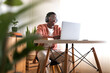 © Daniel - Long shot of young African American man wearing headphones working, studying at home using laptop. Copy space.