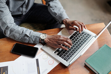 Aufkleber - Above angle of hands of young African American businessman pressing buttons of laptop keyboard while sitting by workplace