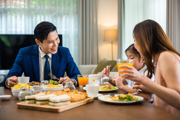 Asian family father, mother with children daughter eating healthy breakfast food on dining table kitchen in mornings together at home before father left for work, happy couple adult family concept