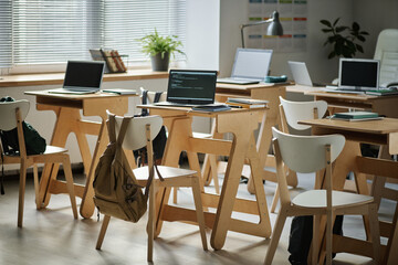 horizontal image of empty class with desks and computers on them for it lesson