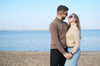 © ribalka yuli - Beautiful young couple posing against the blue sky and water. Couple holding hands and looking at each other