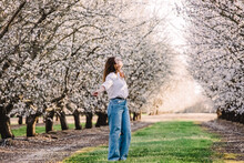 Woman enjoying springtime among blooming almond trees