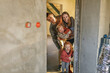 © Westend61 - Happy parents with daughters peeking from doorway