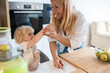 © Panorama - Blonde mother with her blonde hair son playing in kitchen and prepairing some healthy juice
