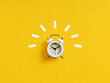 White retro alarm clock ringing on yellow background.