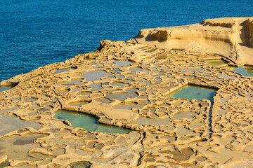 Wall Mural - Salt pans in Xwejni Bay beach on the island of Gozo, Malta. Traditional crafts.