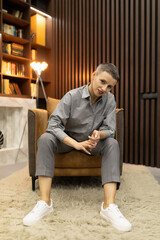 stylish woman at home sitting on an armchair next to the library