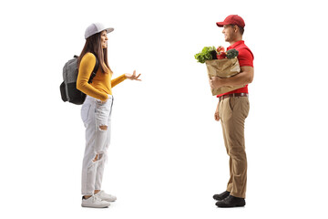 Wall Mural - Full length profile shot of a female student with a backpack talking to a delivery man with a grocery bag