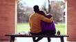 © Marco - Friend embracing girlfriend, black man putting arm around girl sitting at park bench