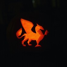 Closeup Of Light Shining Through The Carved Dragon On Halloween Pumpkin On A Dark Background