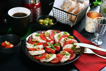 Wall Mural - Caprese salad with mozzarella and tomatoes on black plate and table