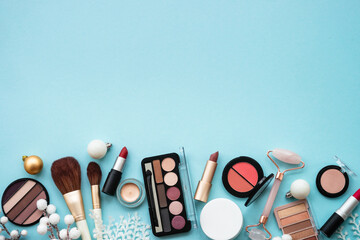 make up products and christmas decorations on blue background. holiday shopping sale concept. flat l