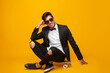 © kegfire - Cool young male sitting on skateboard