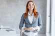 © BalanceFormCreative - Corporate portrait of a successful red hair businesswoman at the office.