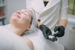© Anna - Cosmetologist and dermatologist cleans the face of a lying woman patient in a beauty salon. Young woman on a cosmetology procedure for facial skin care