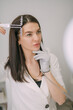© Anna - Portrait of a young beautiful woman beautician in a medical white uniform in her office with cosmetology equipment