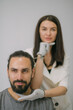 © Anna - Portrait of a young beautiful woman beautician in a medical white uniform and a young bearded man patient