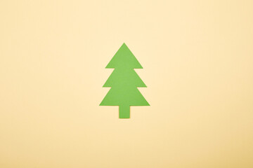 Green Сhristmas tree shape paper applique isolated on the bright solid fond plain yellow background. Postcard template